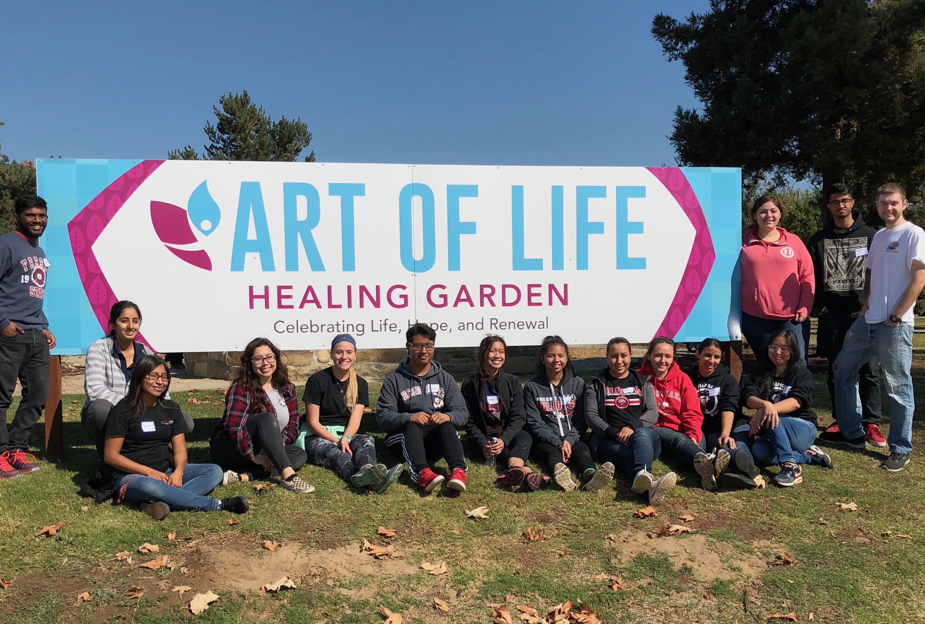 students posing around art of life sign