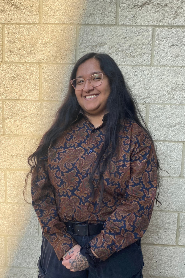 Photo of Ari standing against a brick wall