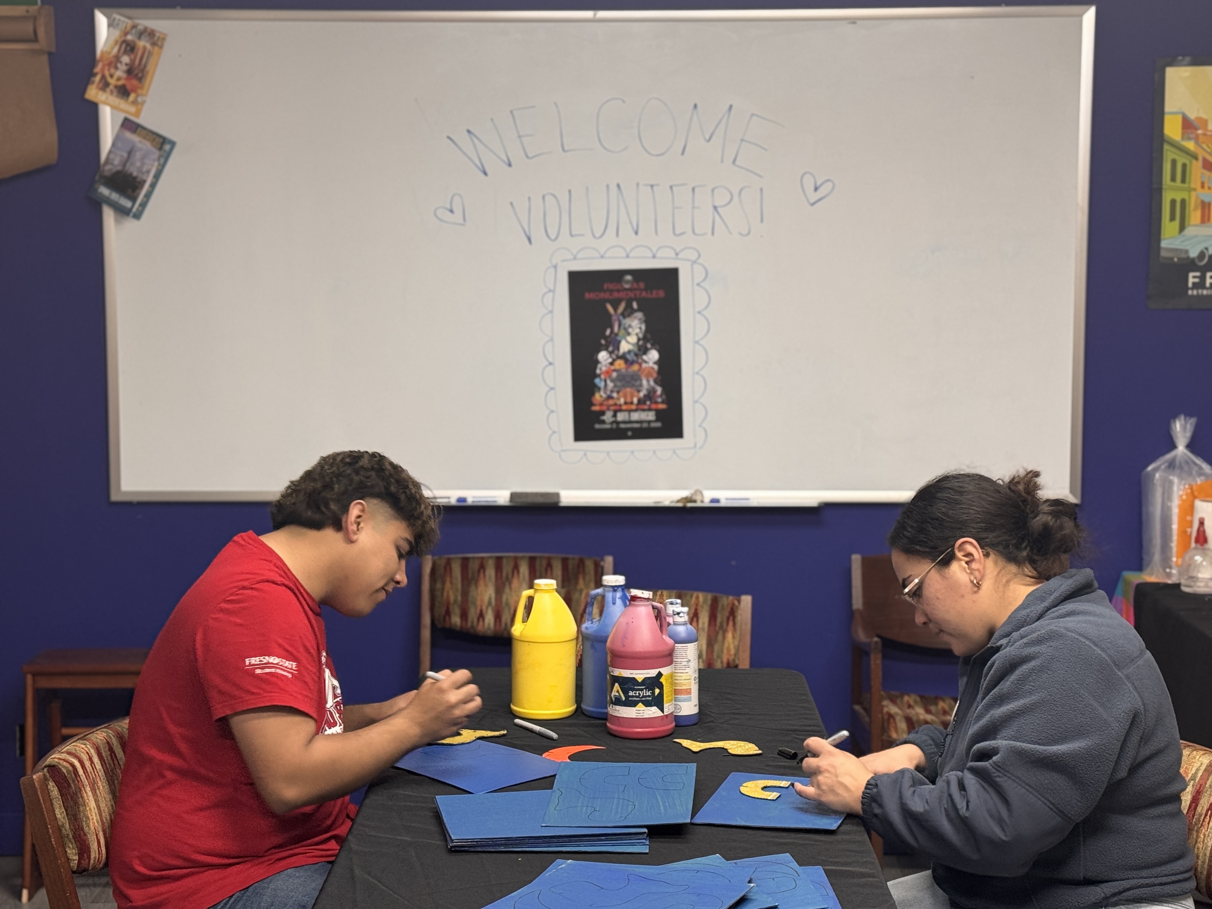 Volunteers paint cardboard for school tour program.