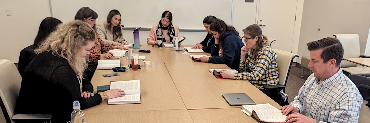 A dozen faculty and staff around a table reading together