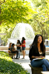 Girl sitting in courtyard with water fountain in background
